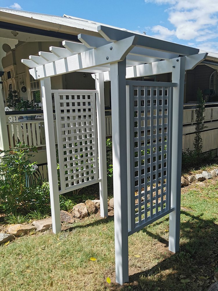 This arbour has had side screening added so that plants can climb up the sides from the gardens on each side.