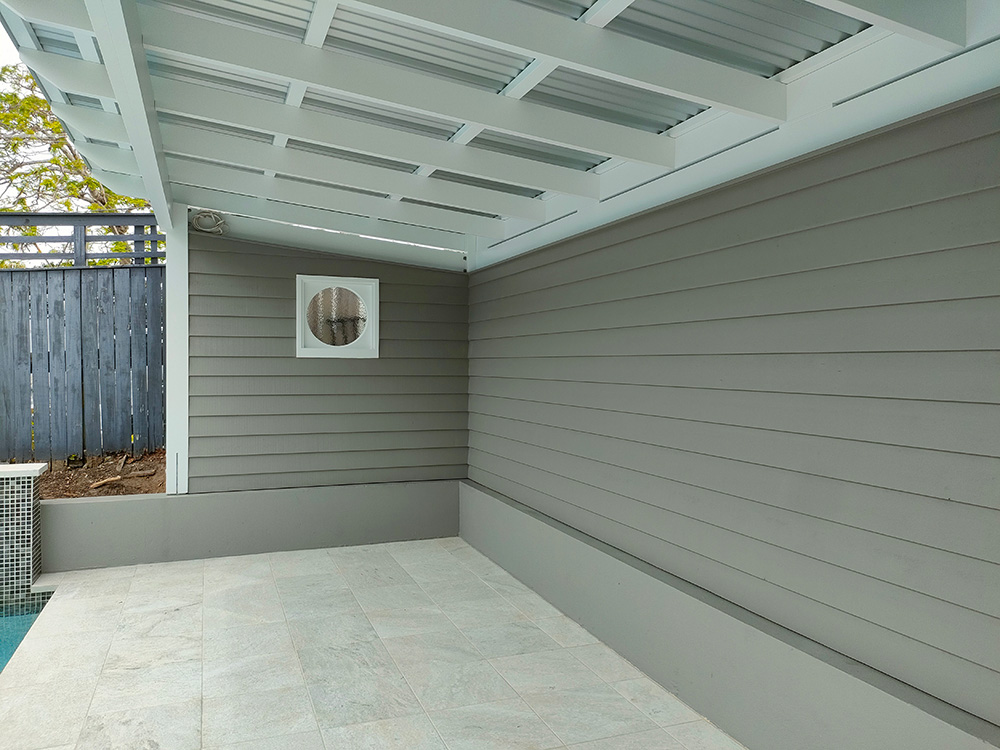 The Cedar weatherboard siding has been fully painted with multiple coats of Quaker Grey Dulux paint color. It looks great with the contrast of the white posts and exposed rafter ceiling.