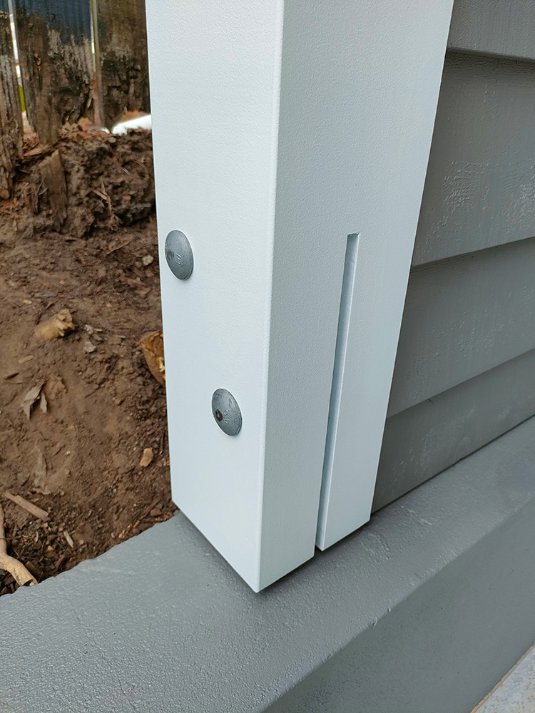 The laminated Pine posts are attached to the structural concrete wall with a galvanized Knife Plate/T Blade brackets. The finish looks great with a very precise cut.