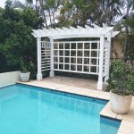 This white Pergola has many features including arched beams, screening and decorative boxes.