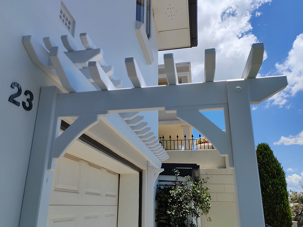 The white Pergola Arbour has knee braces added that create an arched appearance.
