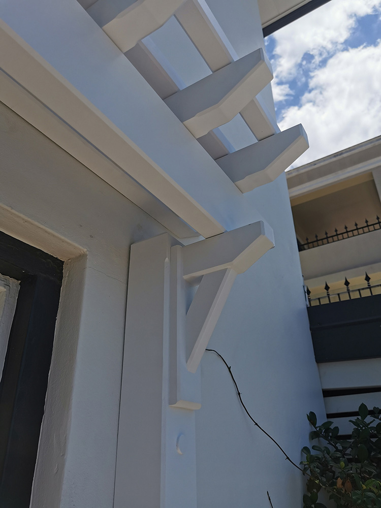 The Eyebrow Pergola has been set just above the garage door with posts on either side.