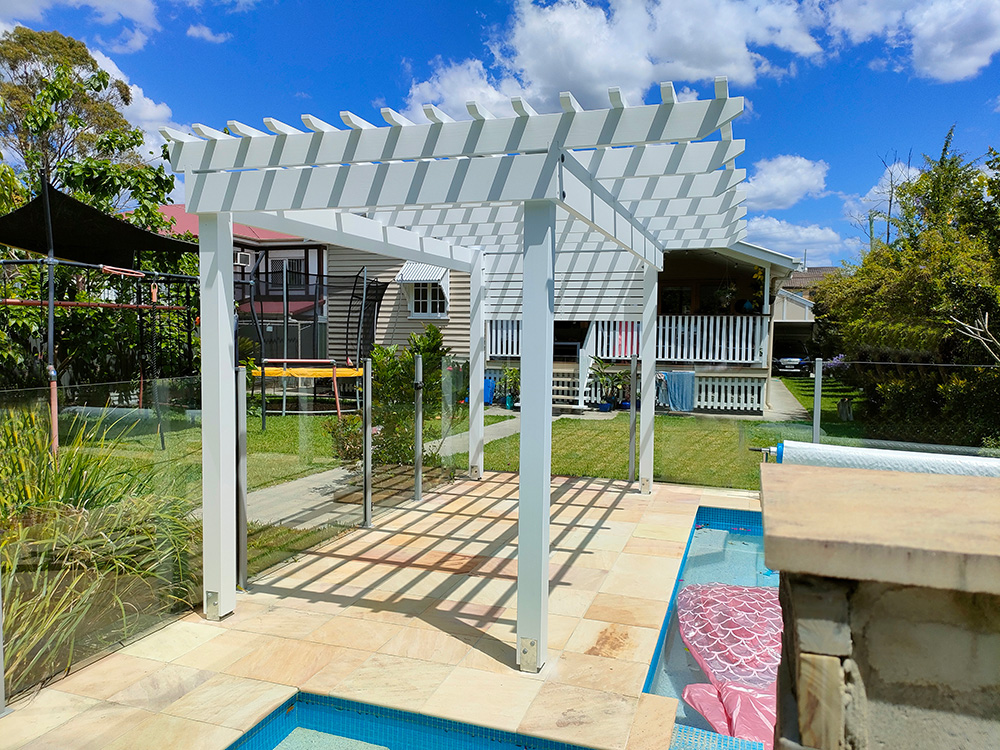 This painted white Pine Pergola fits perfectly into the corner of this pool surround.