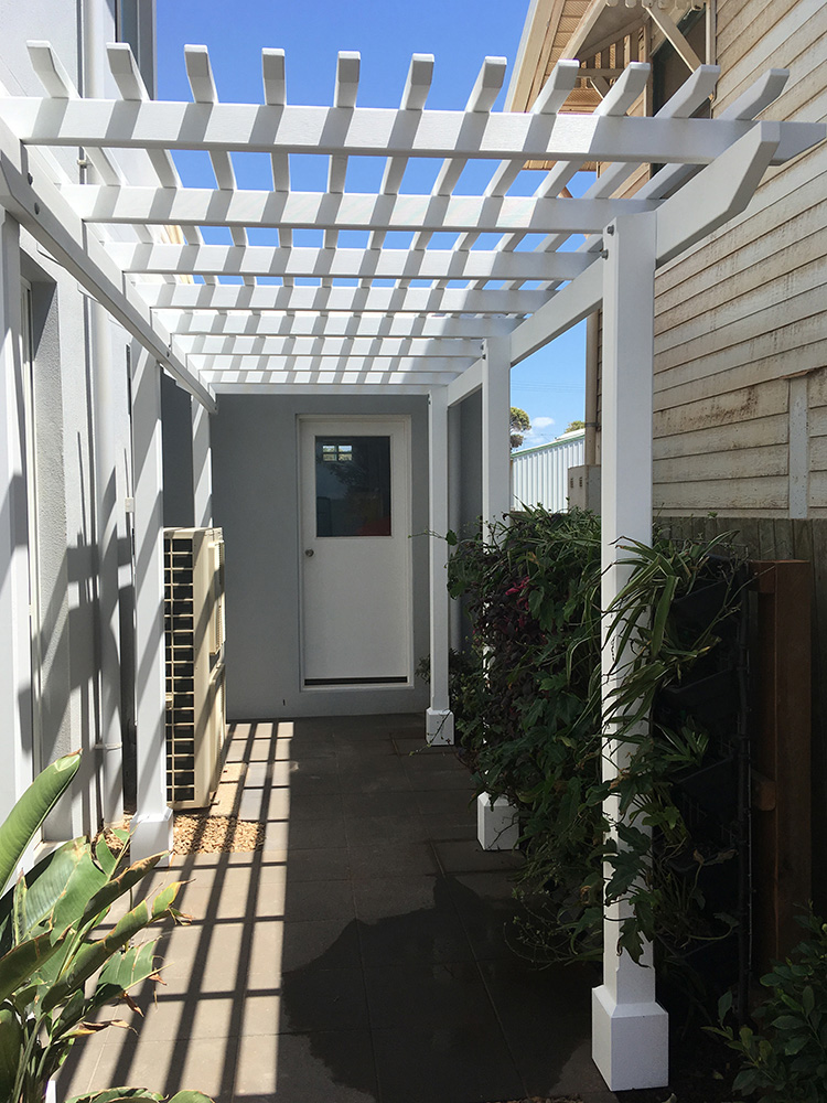White Pine Painted Pergola with tightly set battens for privacy.