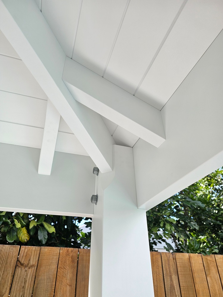 White timber post and beam connection beneath the Cabana’s VJ-lined roof and exposed hip roof framing.