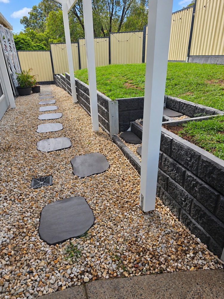 White Pergola posts beside a landscaped path and stepped retaining garden.
