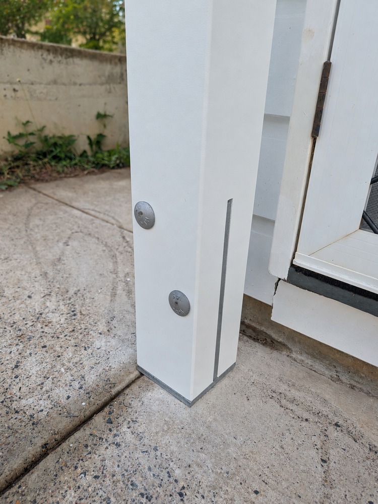White laminated Pergola post fixed beside concrete paving.