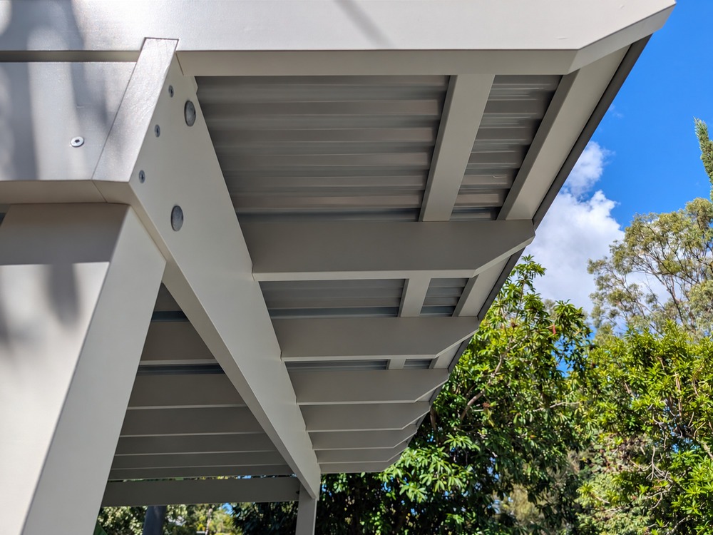 Upward view beneath the Colorbond roof, showing white painted timber rafters, battens and beam.