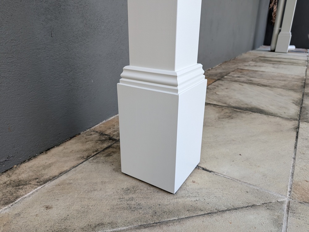 White Decorative Post Box and stepped trim around a pergola post beside the tiled paving.